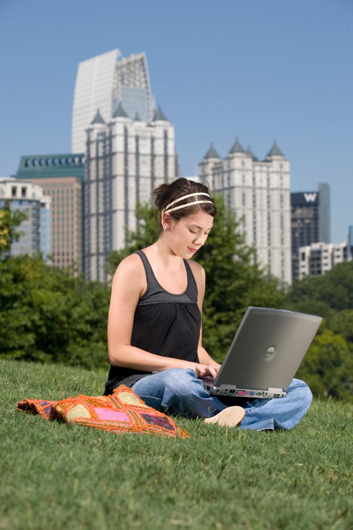 Online student working in the park online student using laptop outside in city park