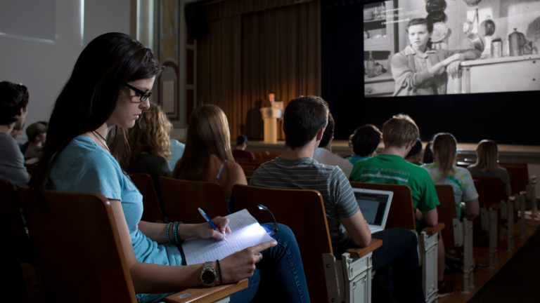 Cinema studies student attending lecture Cinema studies student taking notes during film lecture