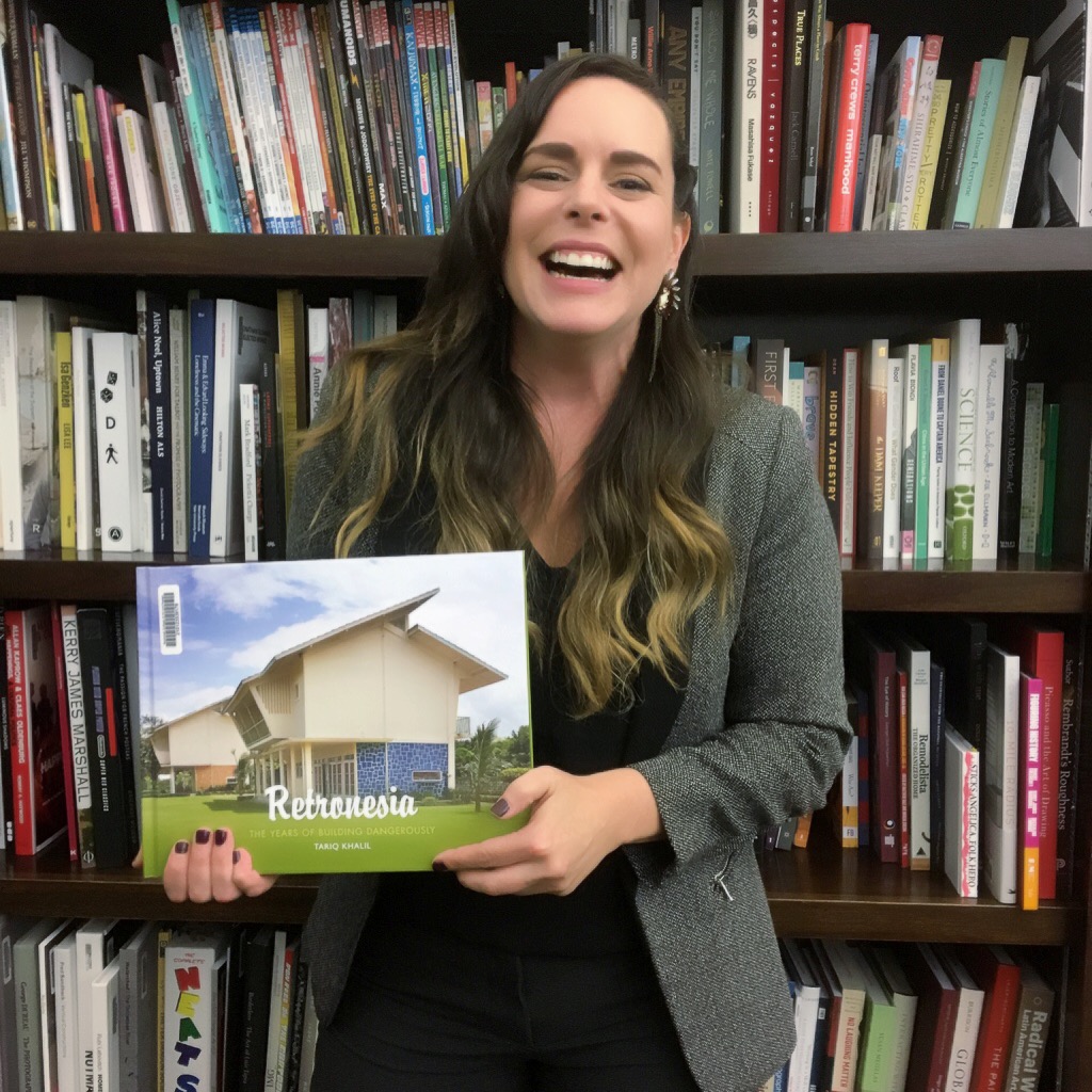 Jackie Dunn smiles broadly while holding book Retronesia