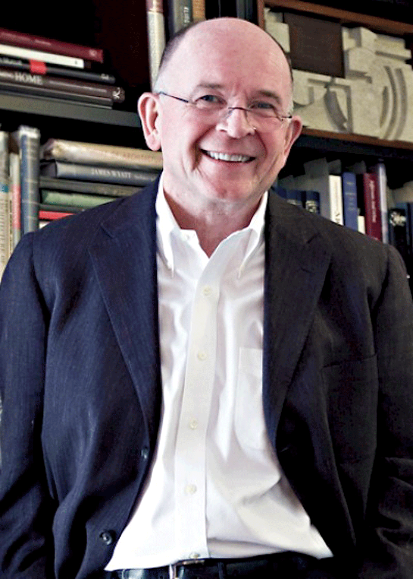 James P Cramer smiles ahead in black suit jacket and crisp white shirt