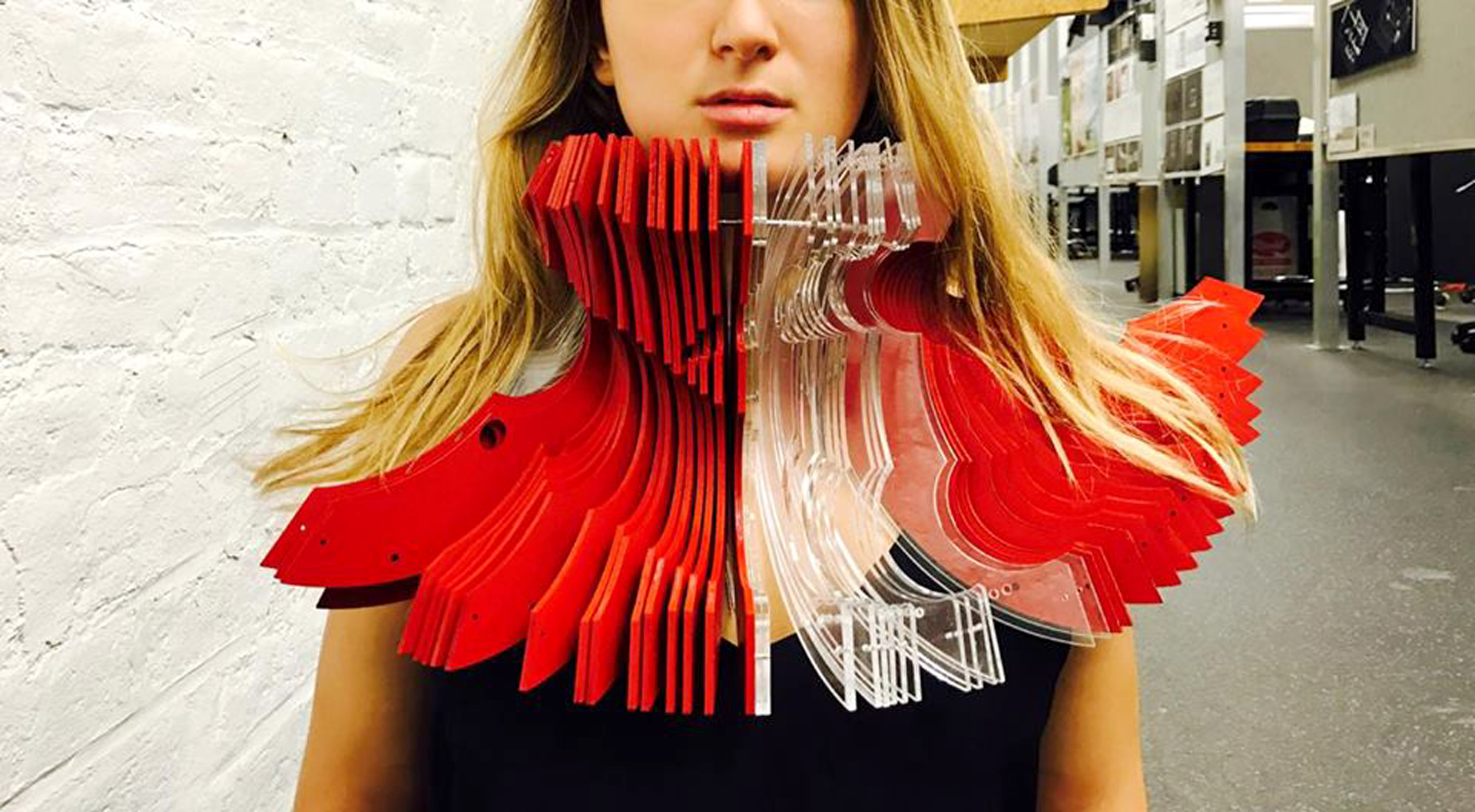 Abstract hat worn around the neck and made up of red and translucent layers