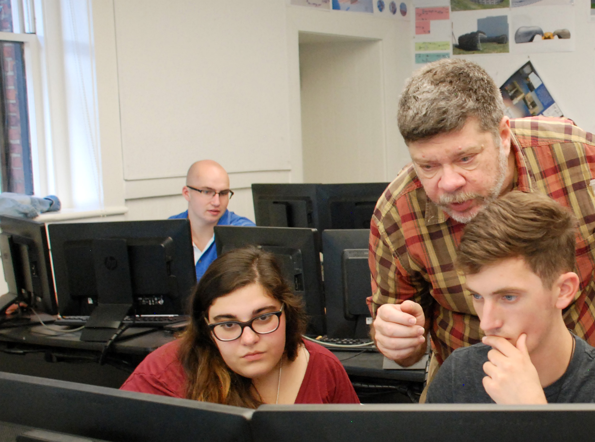 Herzer looks over the shoulder of two students on computers