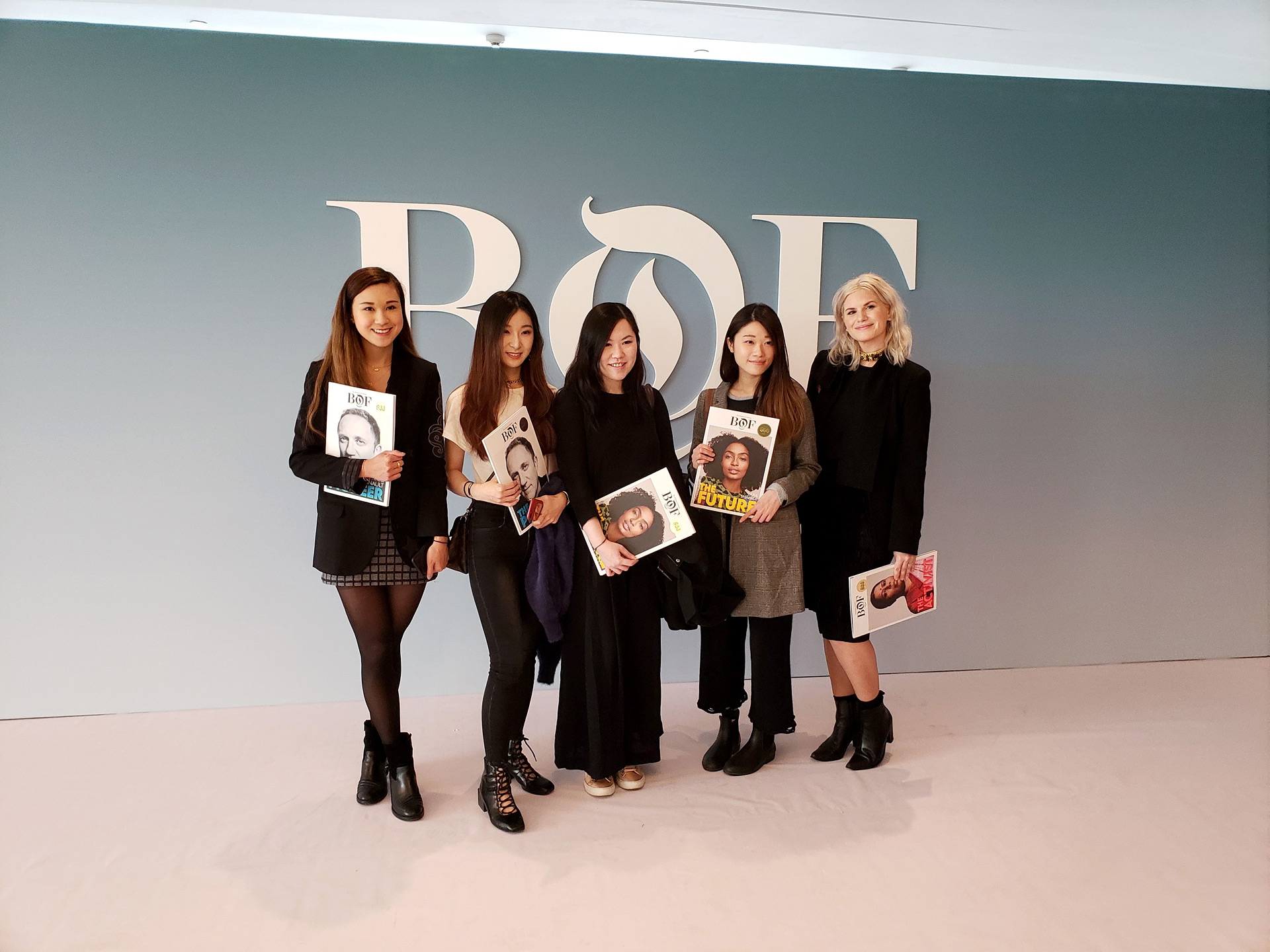 Five students smile while holding Business of Fashion magazines