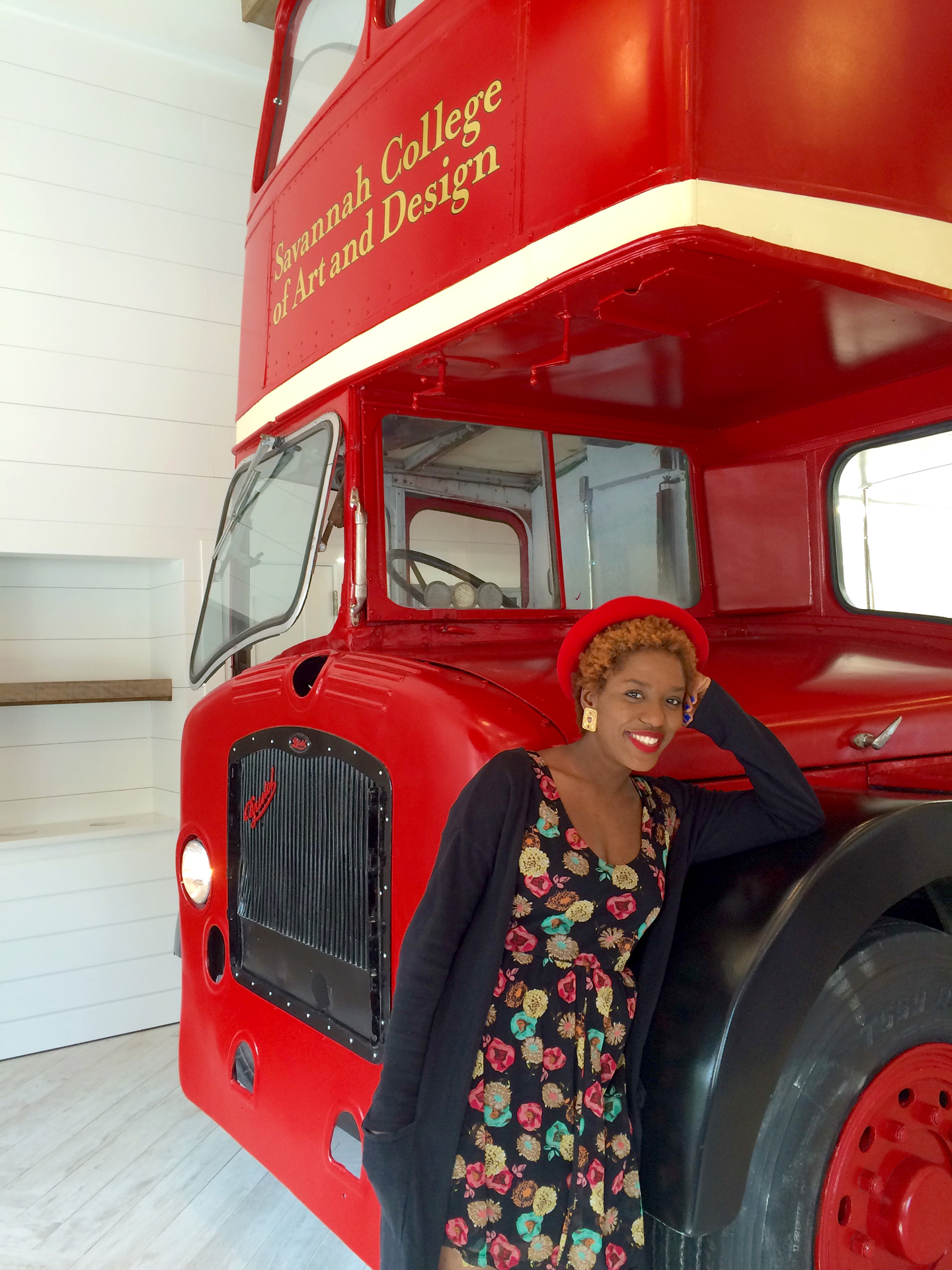 Alumna Merline Labissiere in front of red double decker bus at Art's Cafe, Savannah
