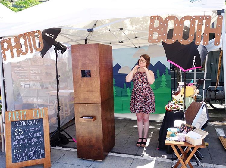 Audra Osborne poses with her hands under her chin the middle of a photo booth set