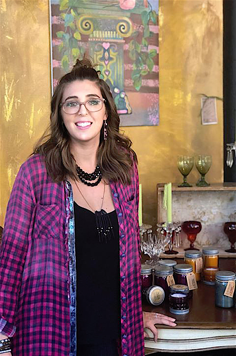 Mollie Youngblood leans on a table full of decorative candles in her store