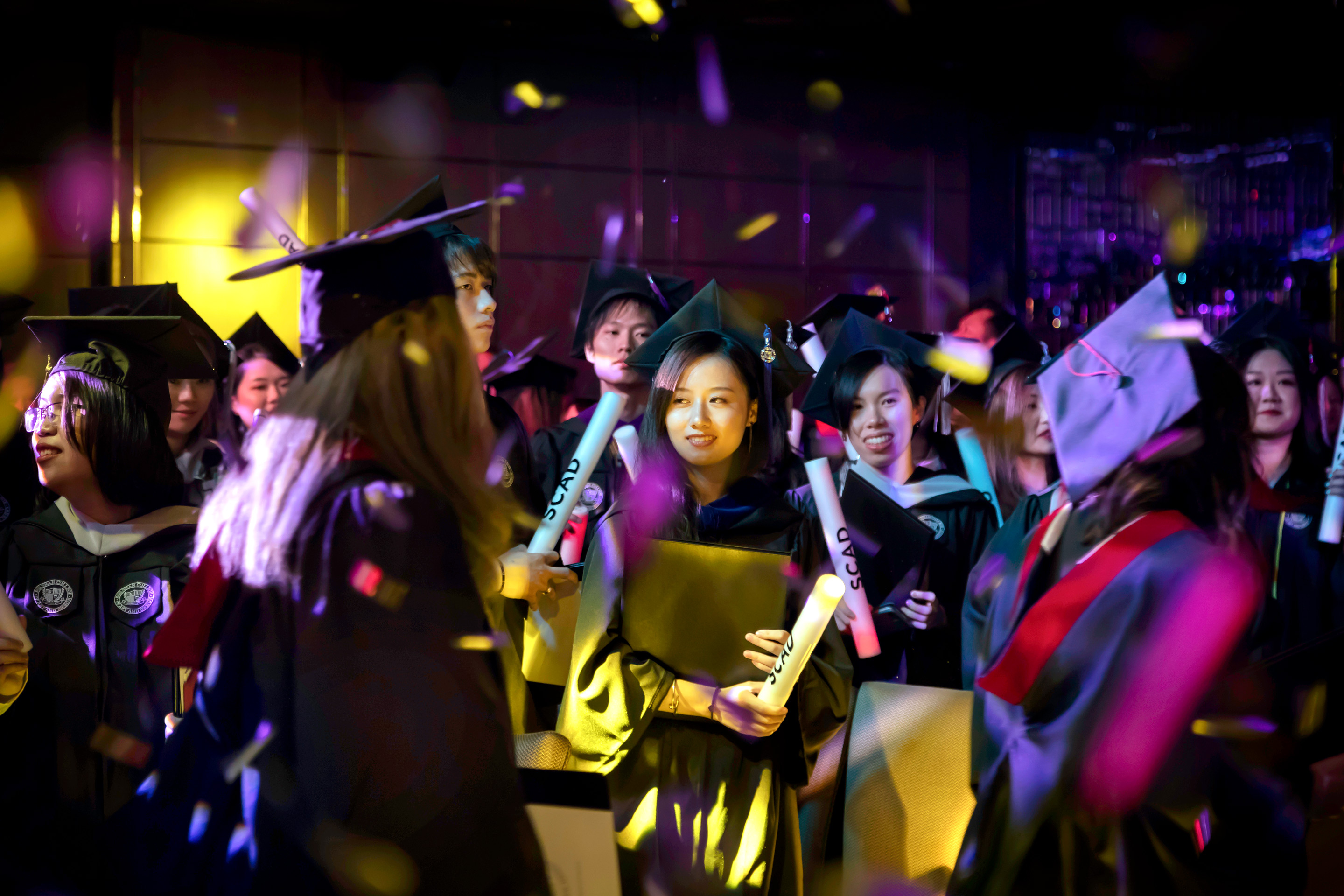 Group of students in cap and gowns hold diplomas