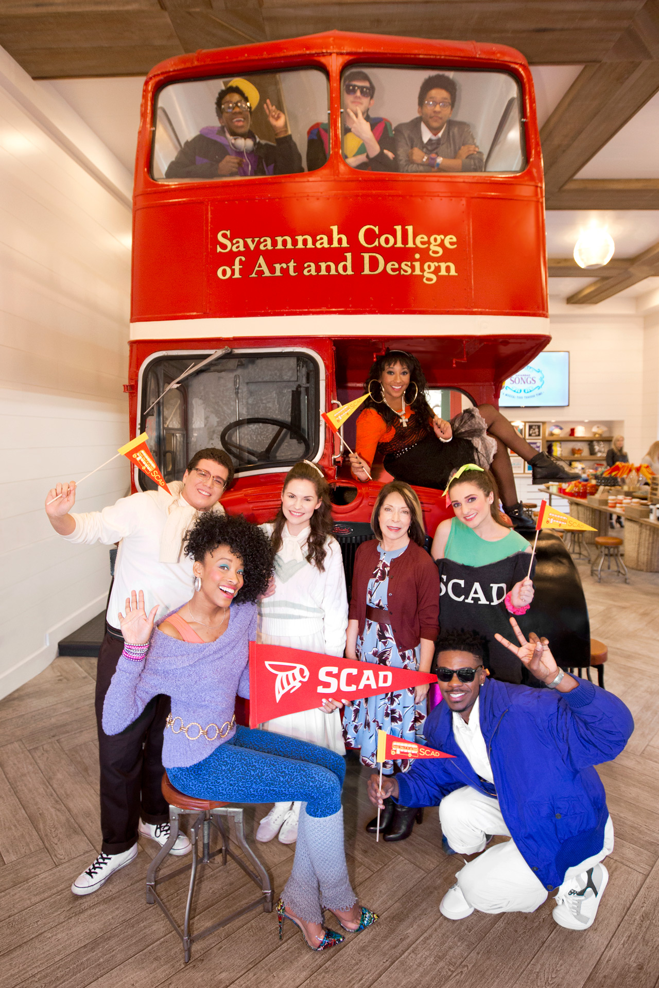 SCAD students in 1980s dress hold SCAD pendents pose with university founder and president in Art's Cafe