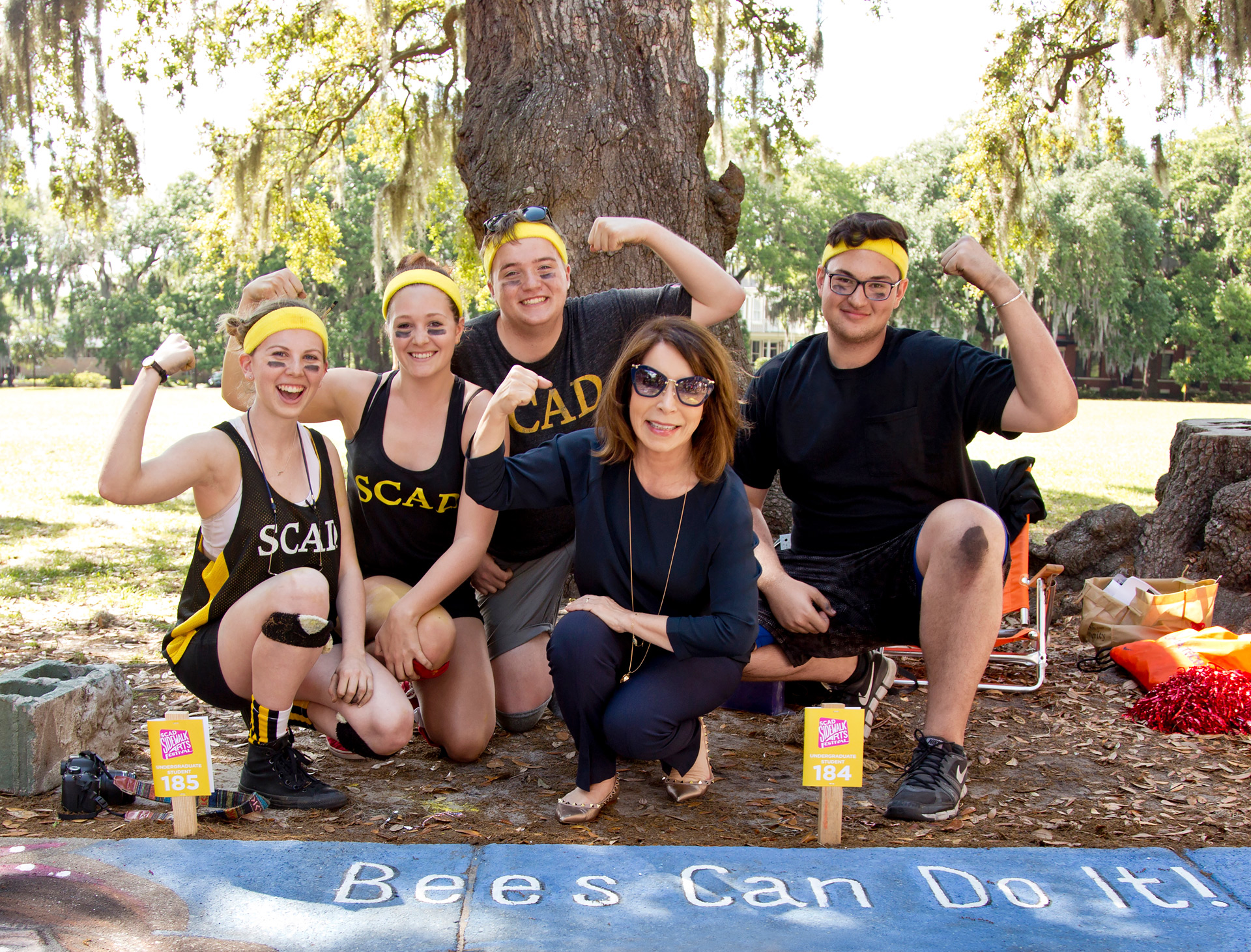 SCAD founder and president poses with students at the annual sidewalk chalk festival