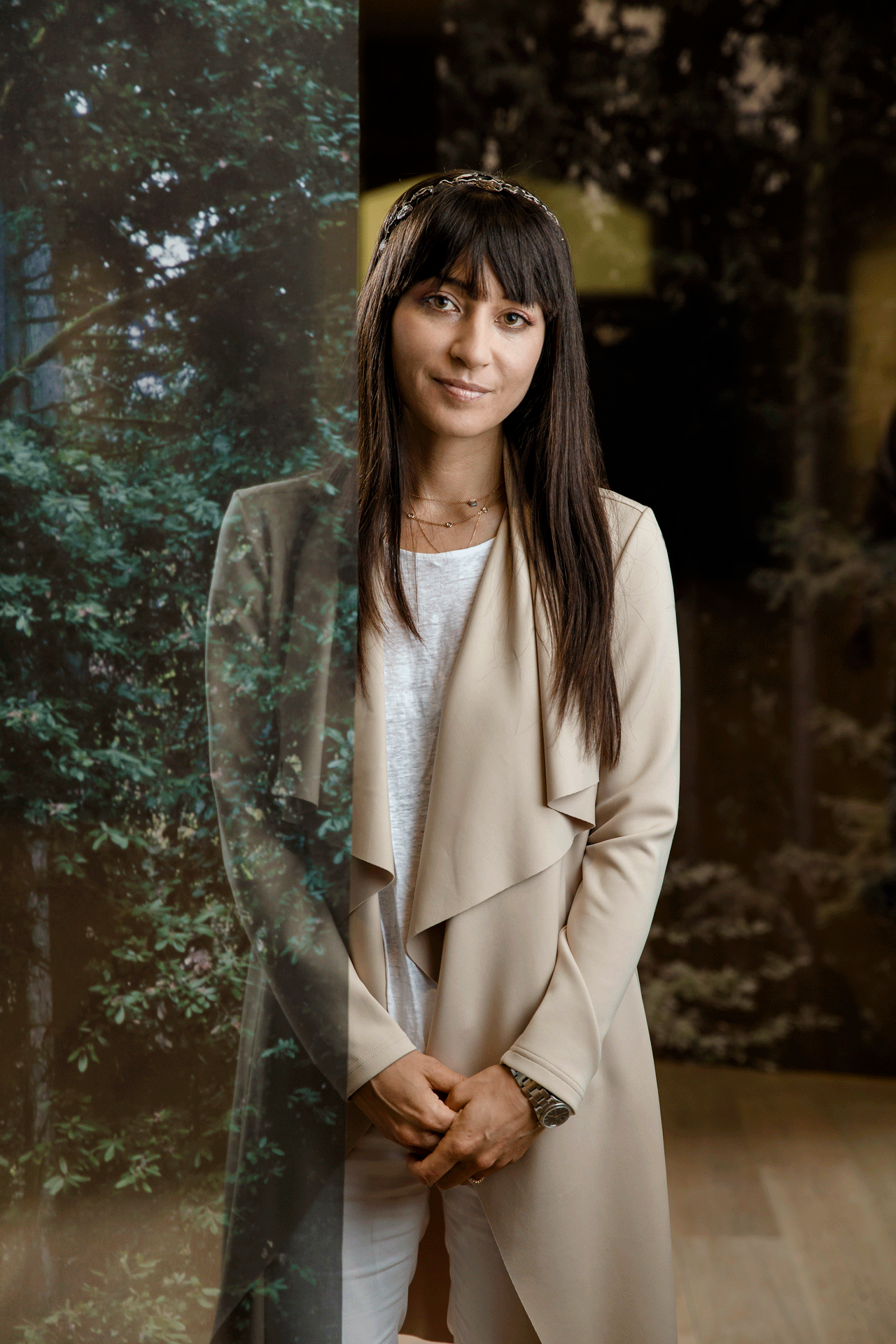 Miyo Ando poses amongst her work, half her body is covered by transparent panels featuring images of redwoods