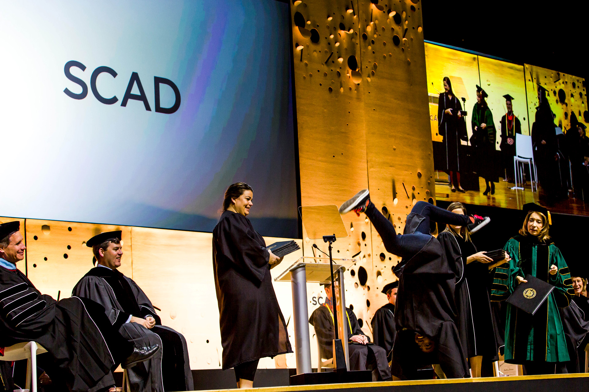 Graduate does handstand on stage