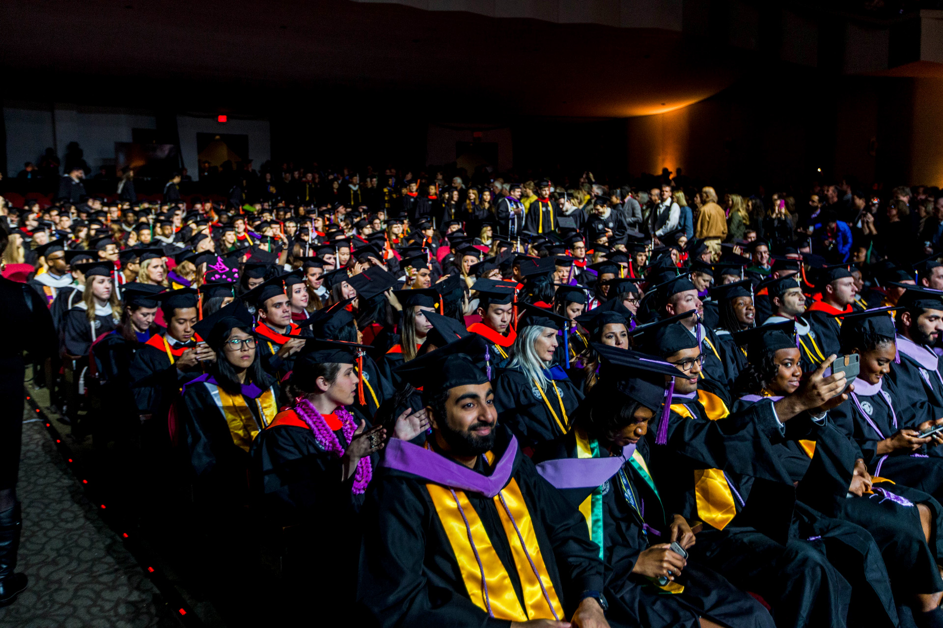Graduates in cap and gown sit in audience