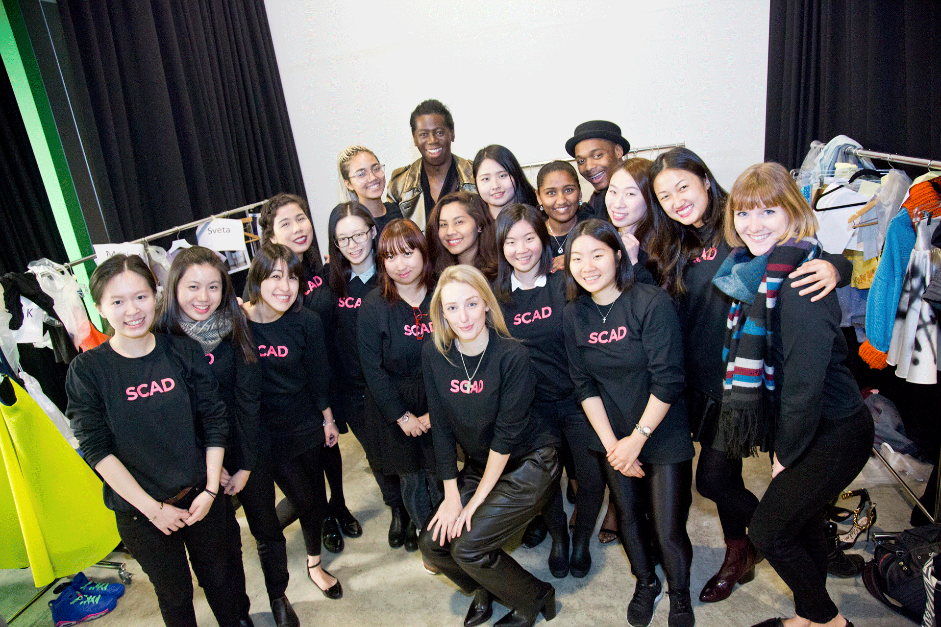 Students in black SCAD shirts pose together backstage