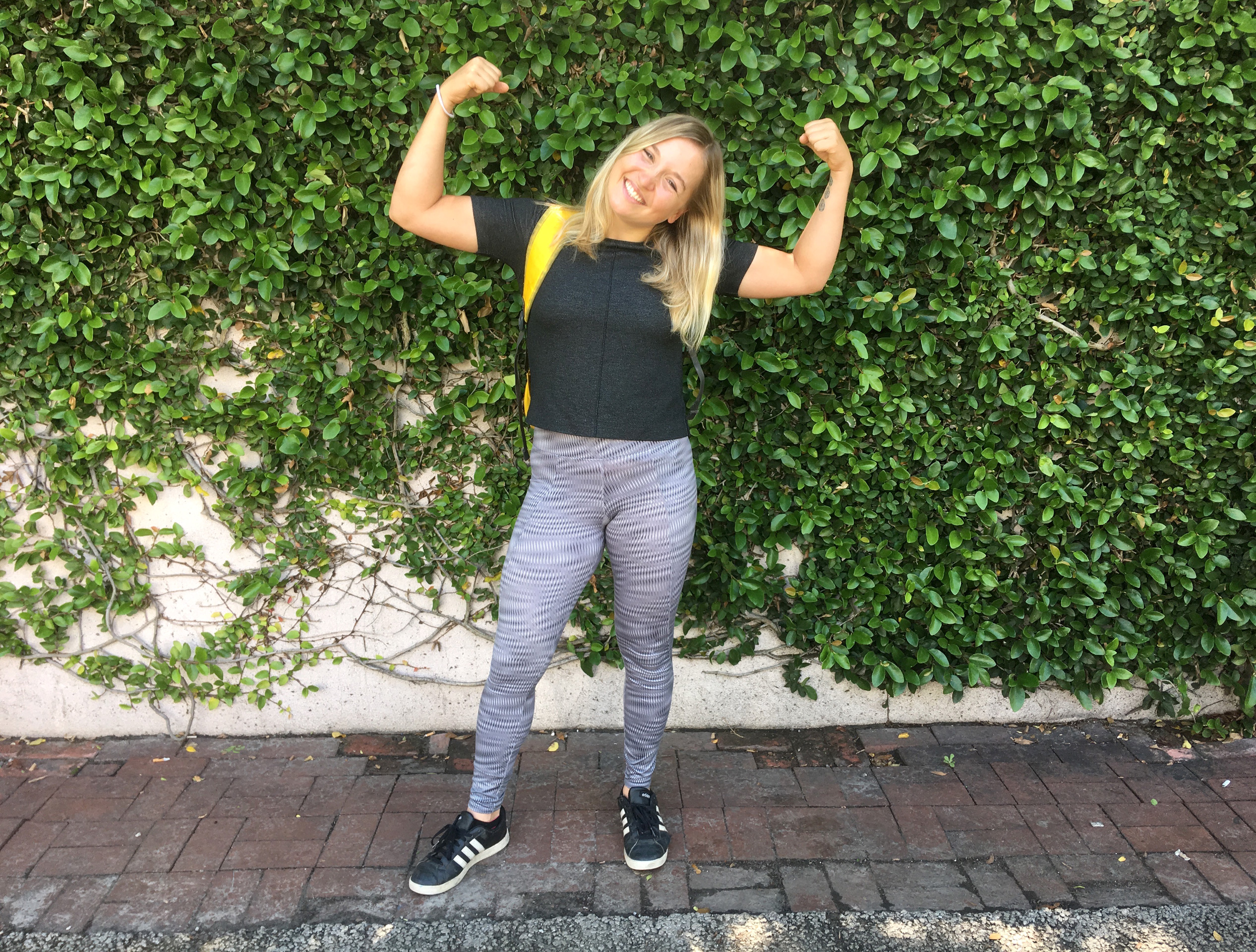 Student flexes muscles in front of vine covered wall