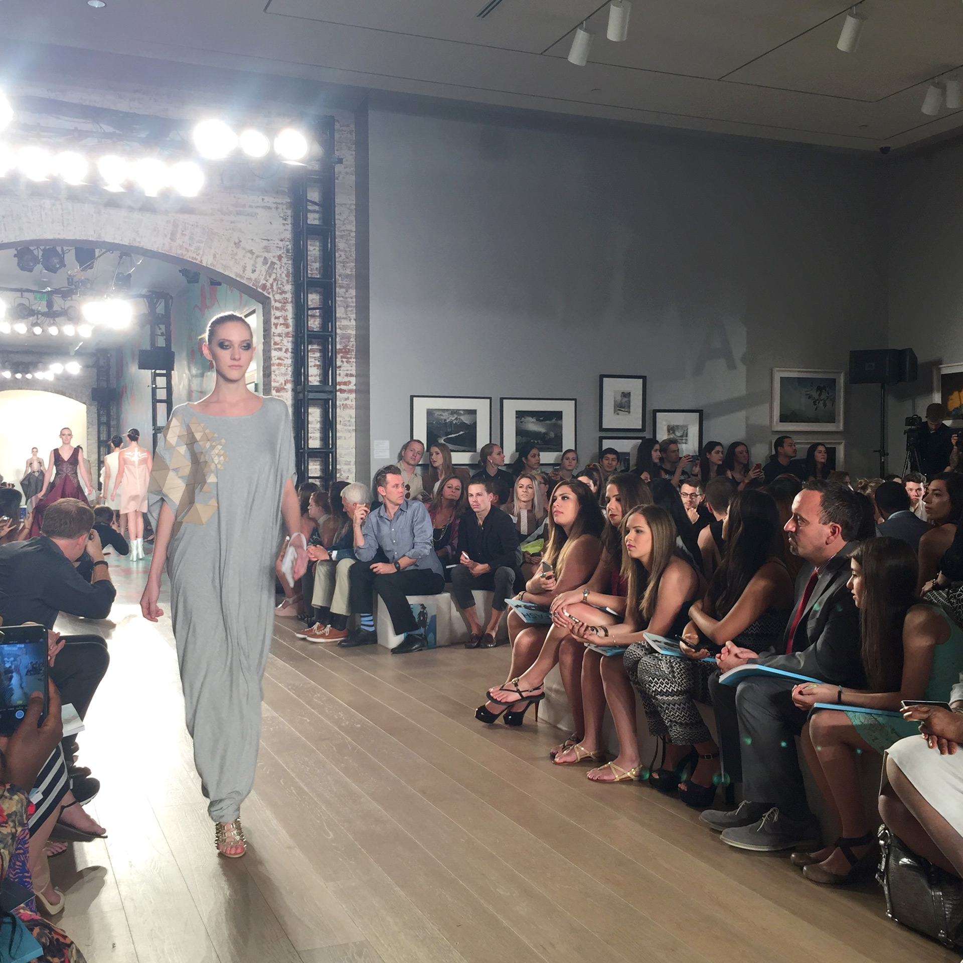 Model wearing Molly Sayers' garment walks down the runway to a crowded audience