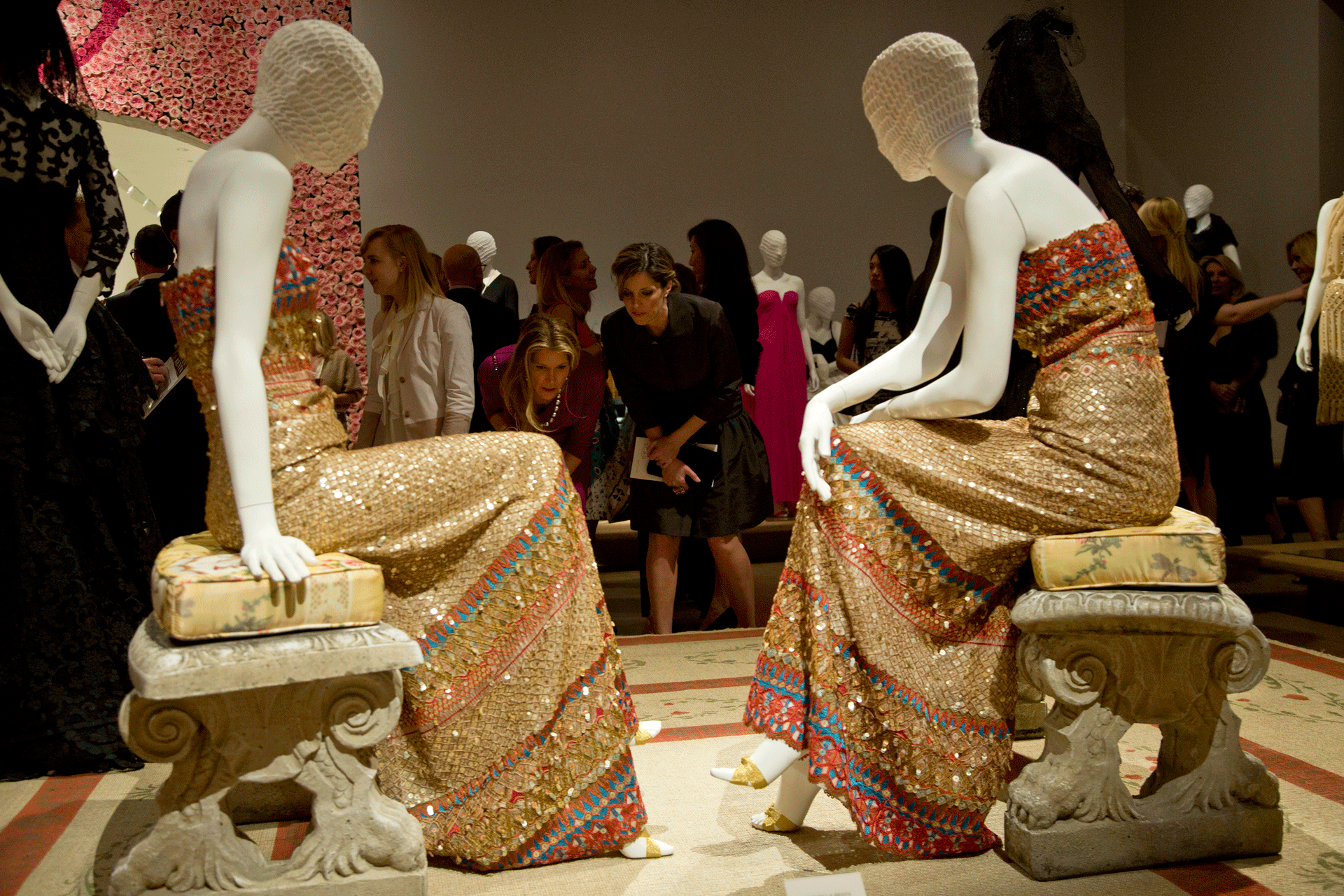 Two women read label in front of two Oscar de la Renta dresses on mannequins at SCAD Museum of Art