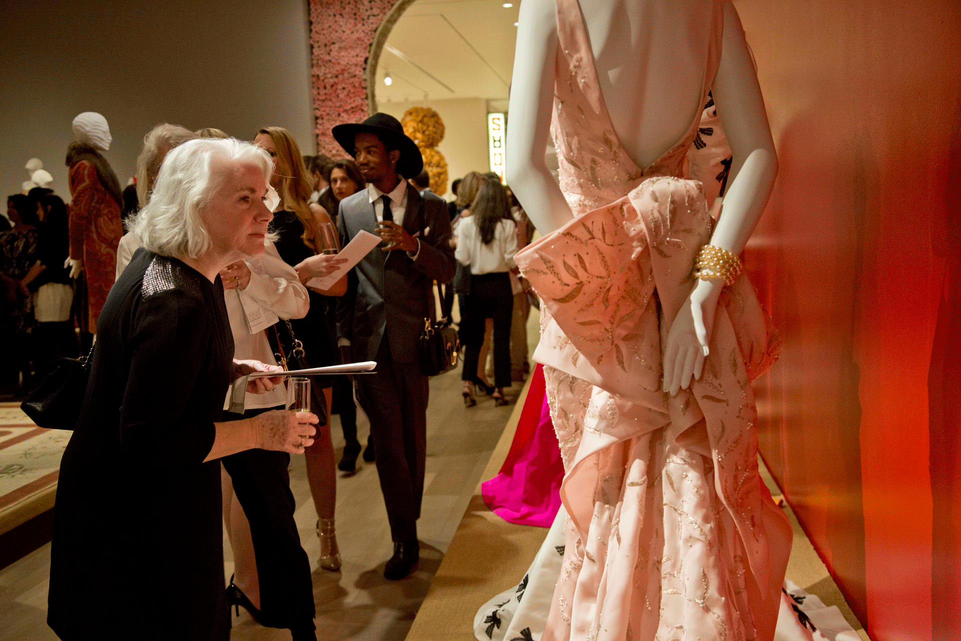 Woman takes a closer look at pink Oscar de la Renta dress on display at SCAD Museum of Art