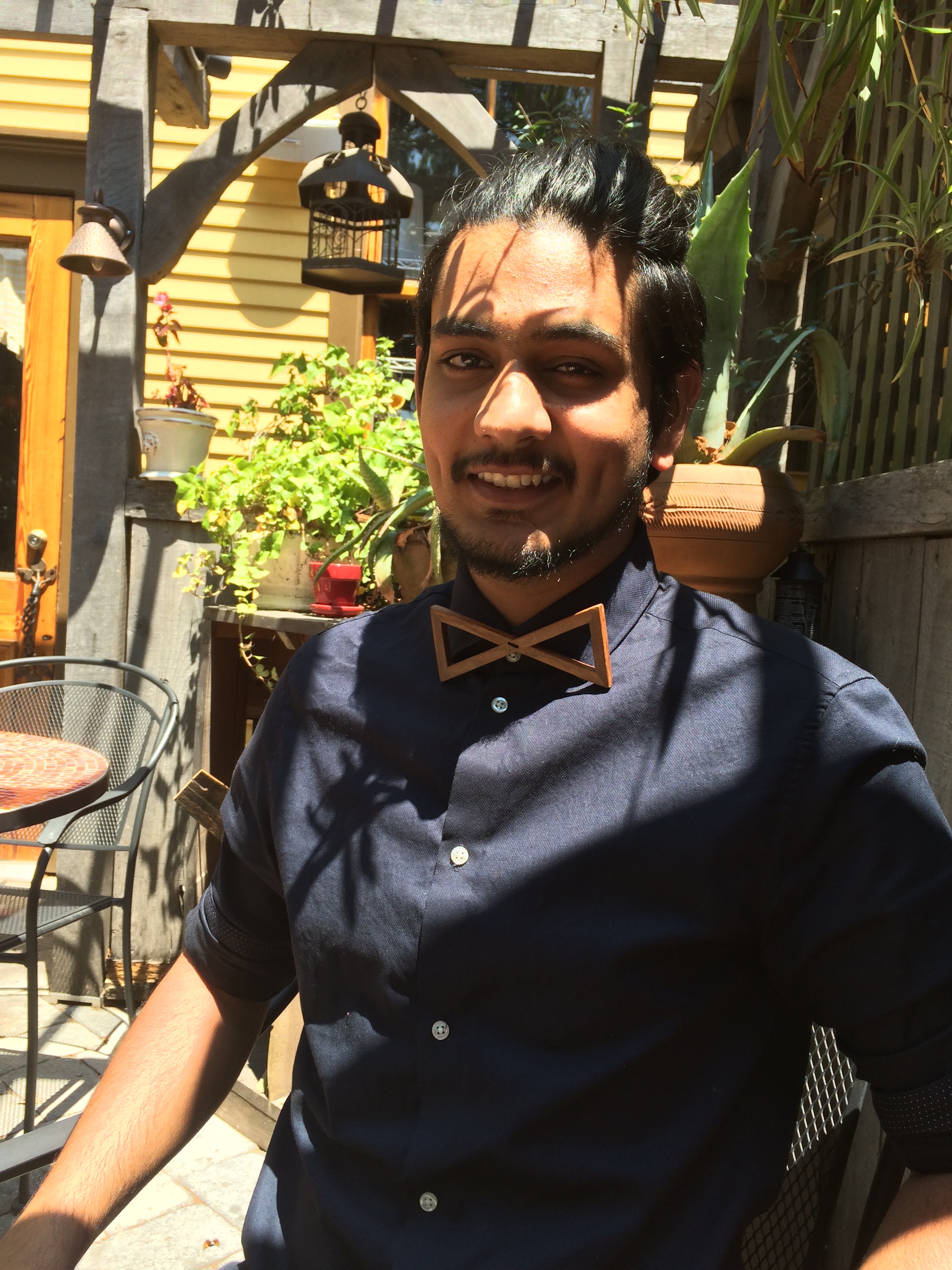 Chaudhary sits in outdoor cafe wearing one of his wood bow ties
