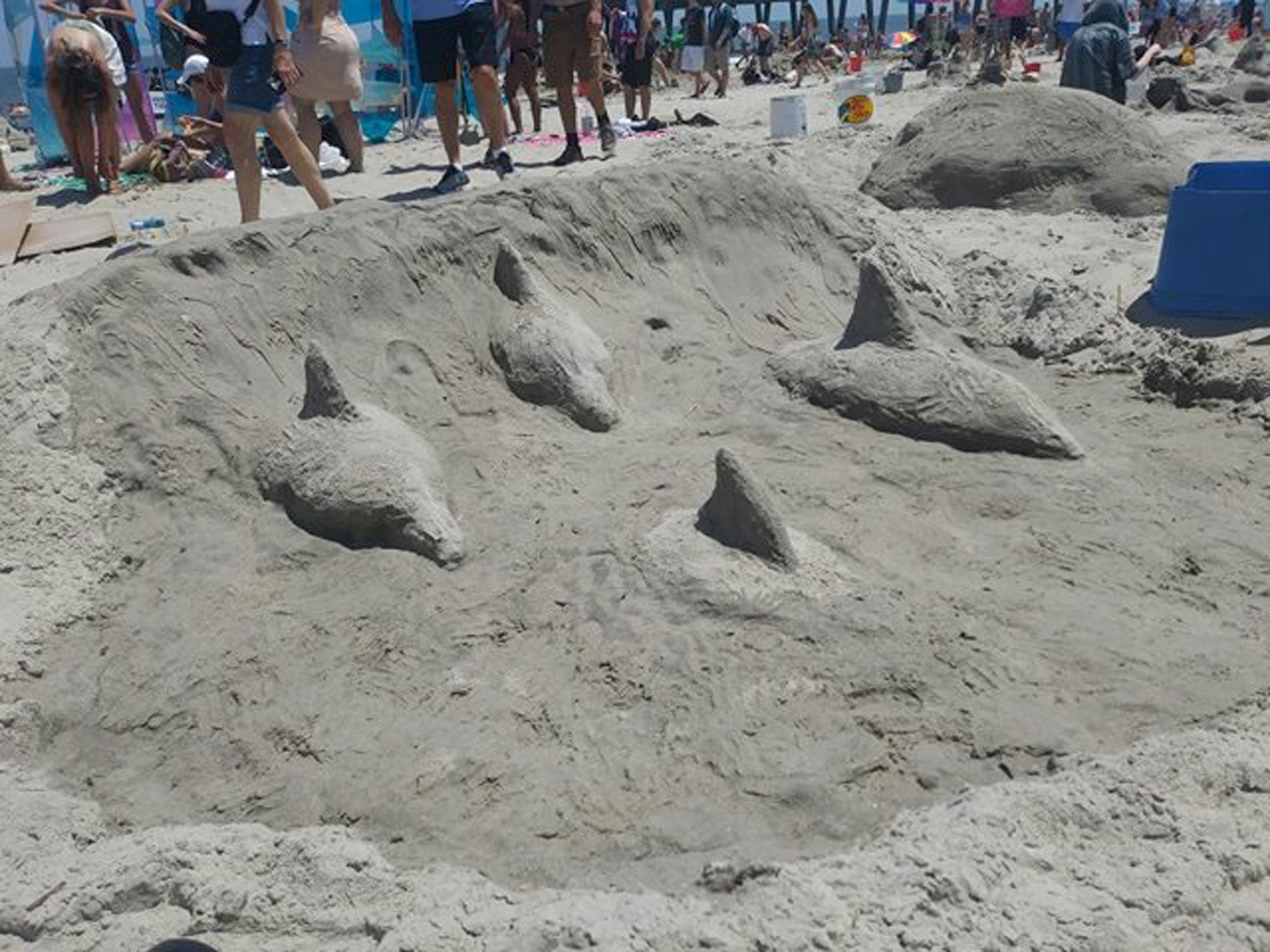 Sand relief of dolphins surfacing from a wave