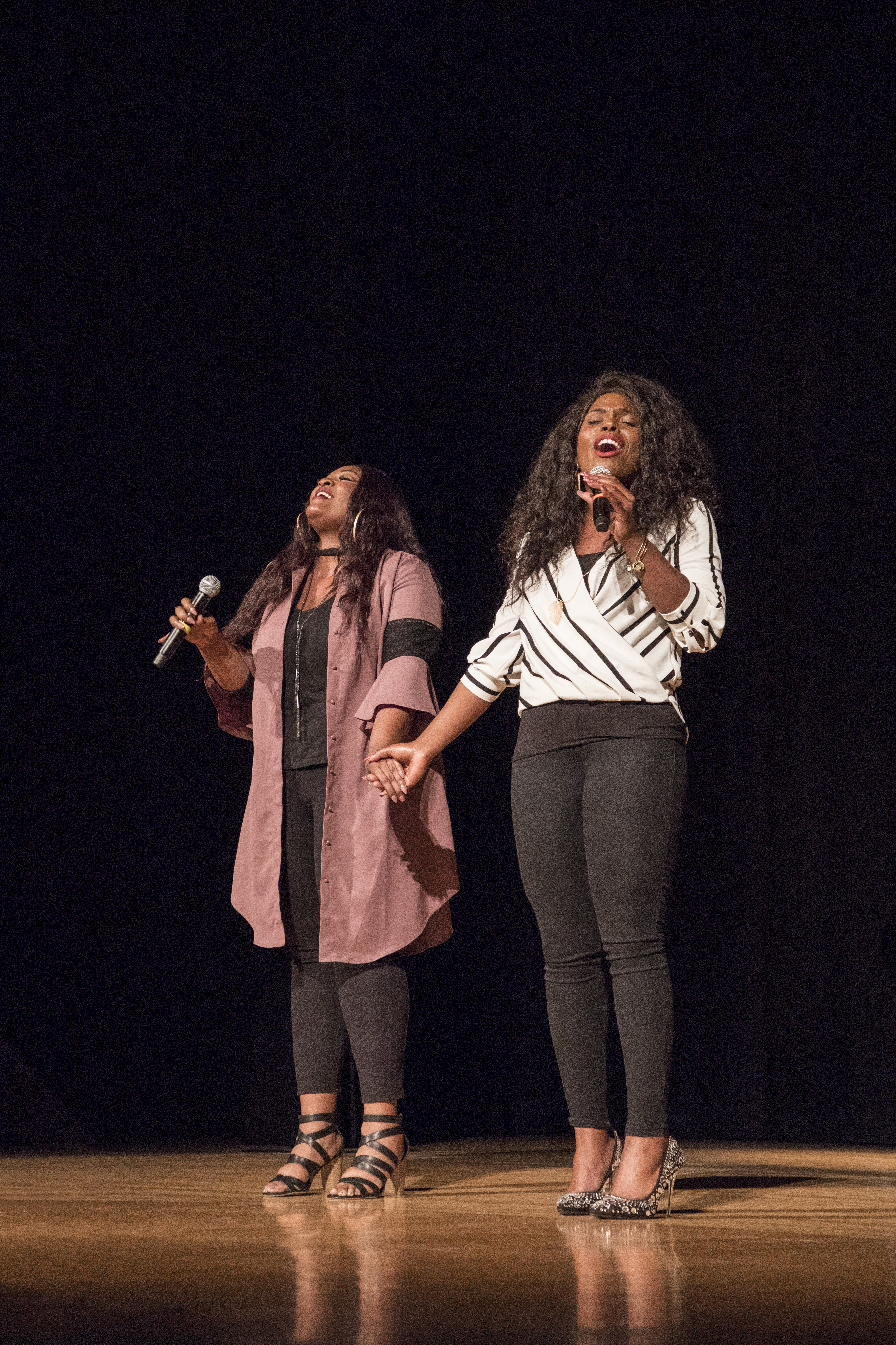 Glover and Lee hold hands while they sing on stage