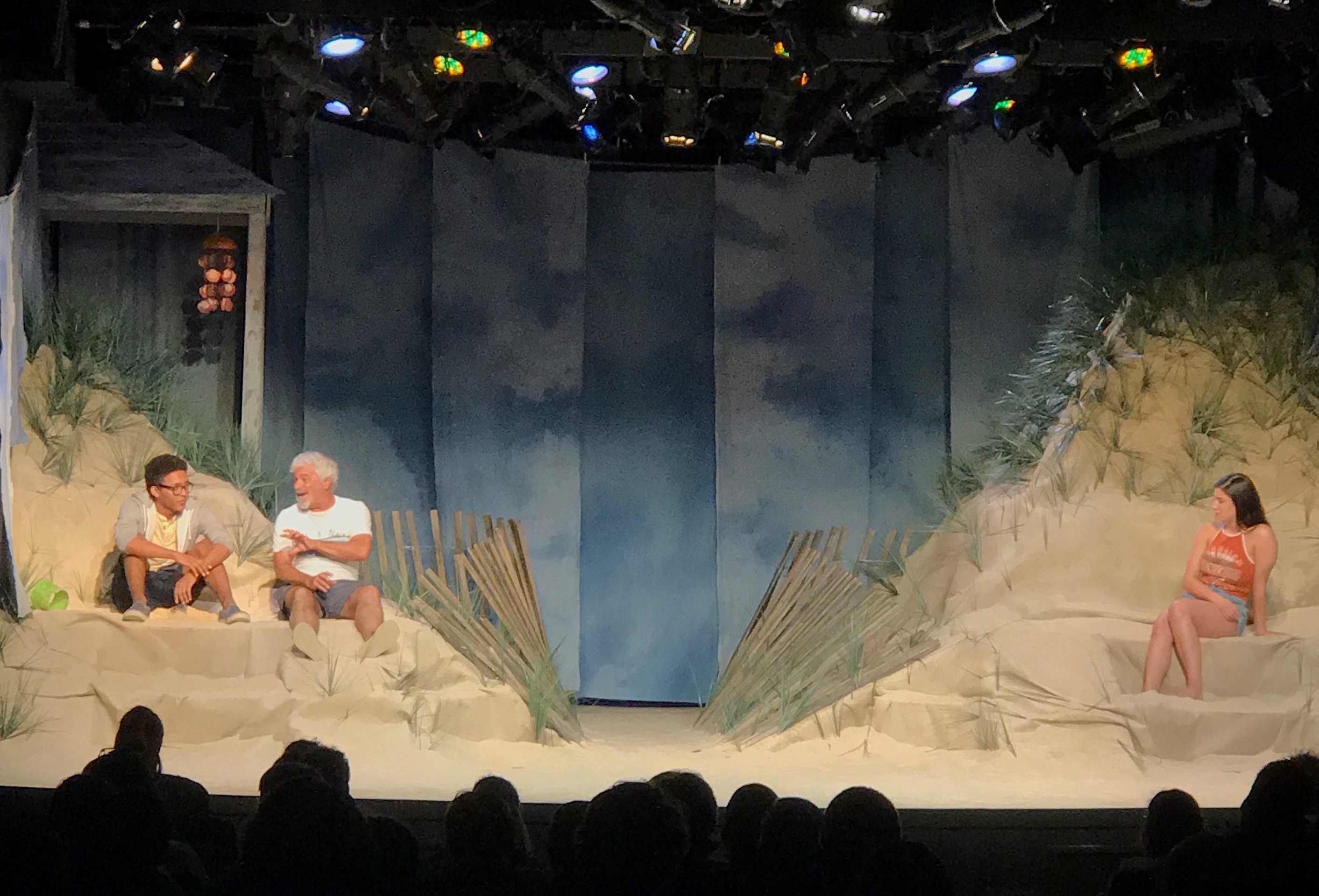 Theater-goers look on at a beach set design