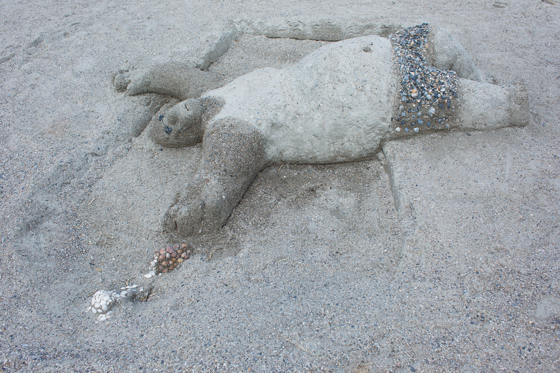 Sand sculpture of sunbathing beachgoer 
