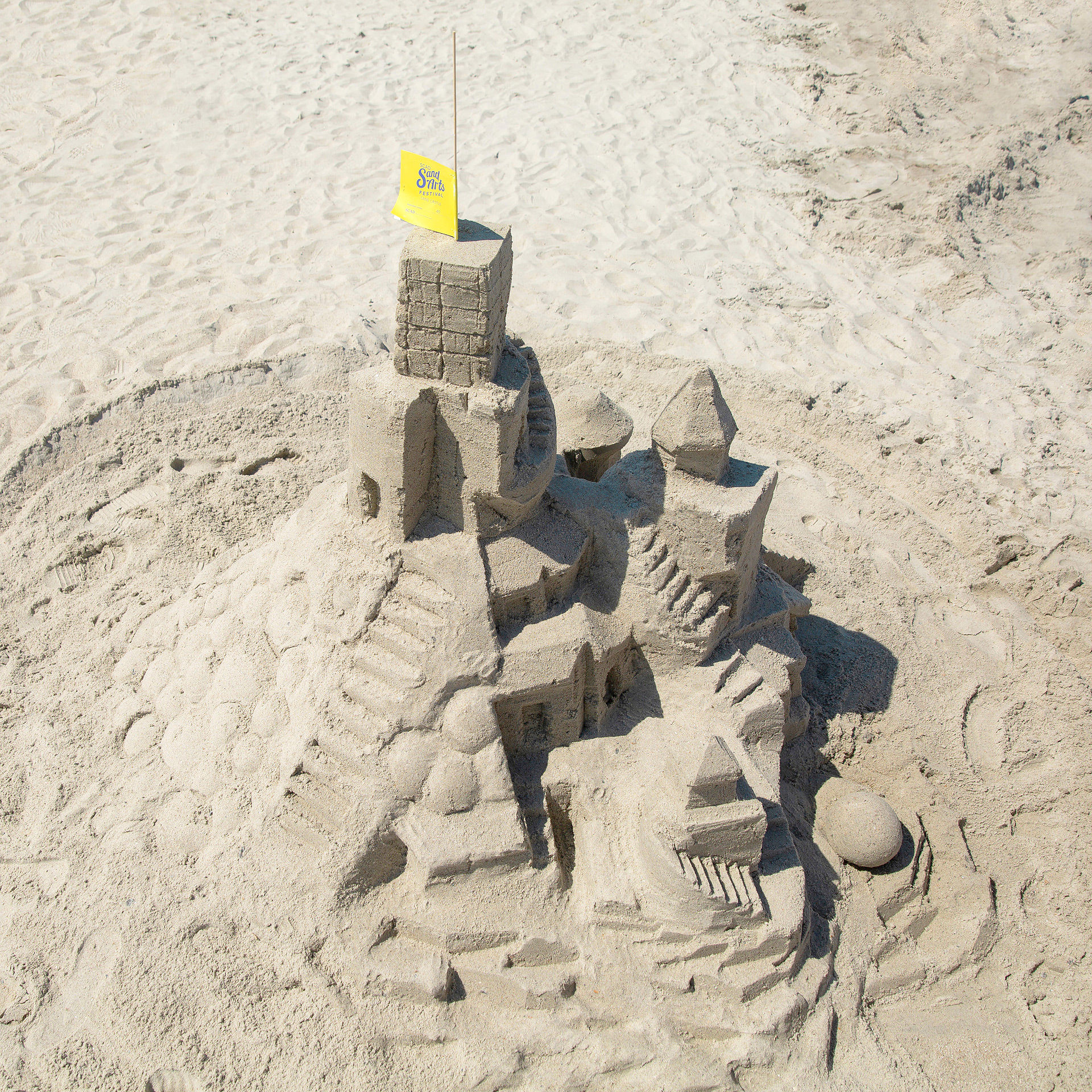 Tall sand castle with yellow flag at top