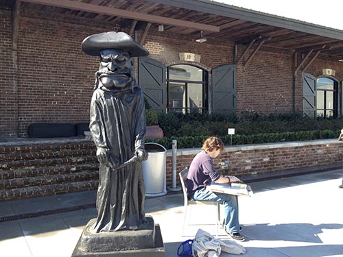 Student sketches next to outdoor sculpture by Nathan Mabry