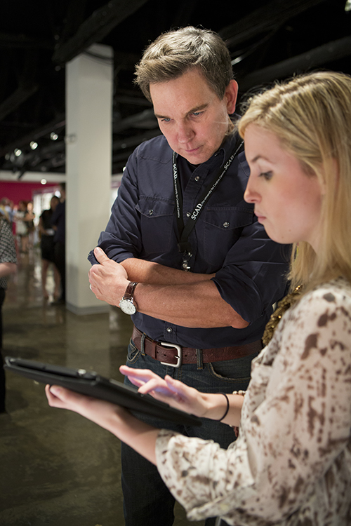 Student holds tablet for visitor to look at