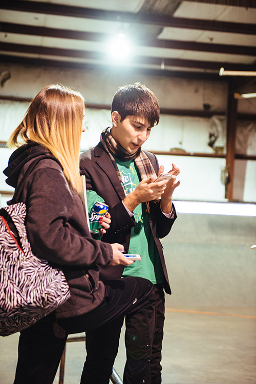 Students look at cell phones on the film set