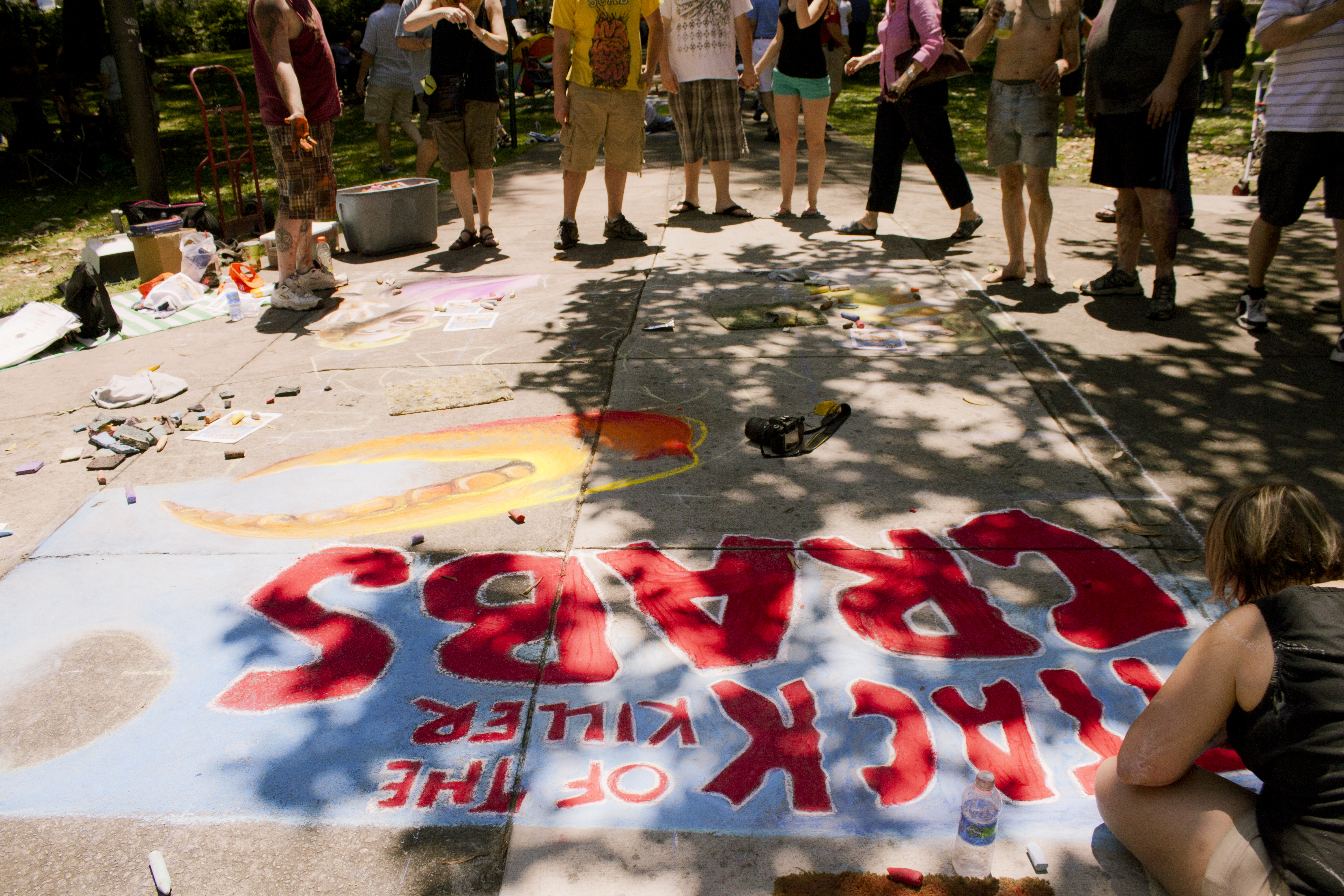 Participants work on a large-scale sidewalk chalk artwork featuring killer crabs
