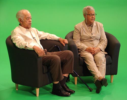 Husband and wife sit in front of green screen 