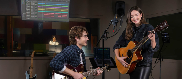 Two students on guitar in recording room.