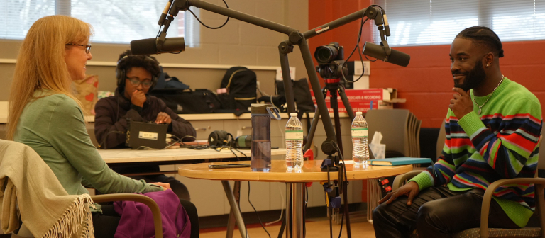 Three people around a table recording stories.