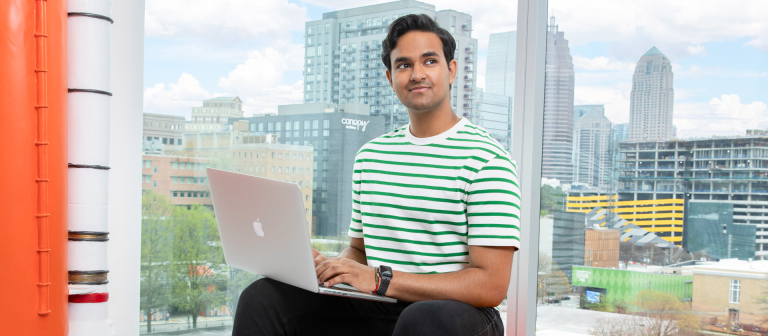 student working on computer with skyline in background