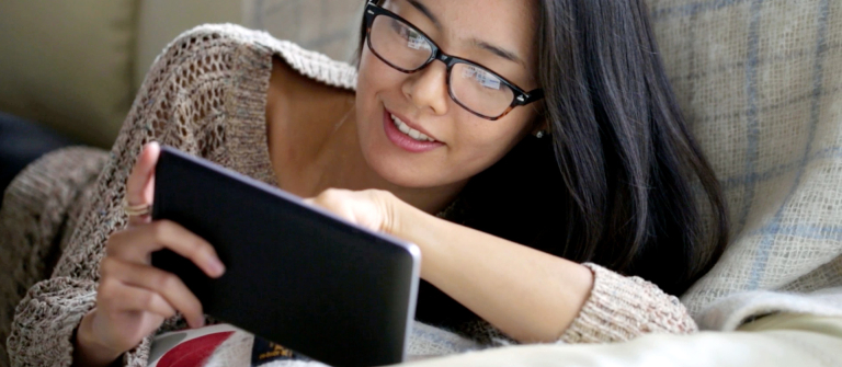 Lounging woman looks at tablet