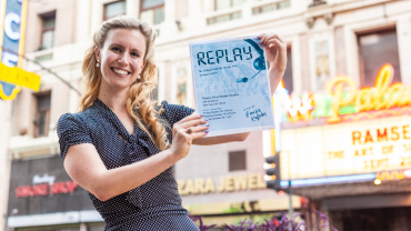 Emilie Kefalas holding Replay poster