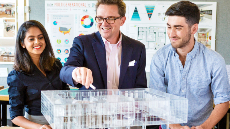 Architecture faculty reviews scale model of building with students