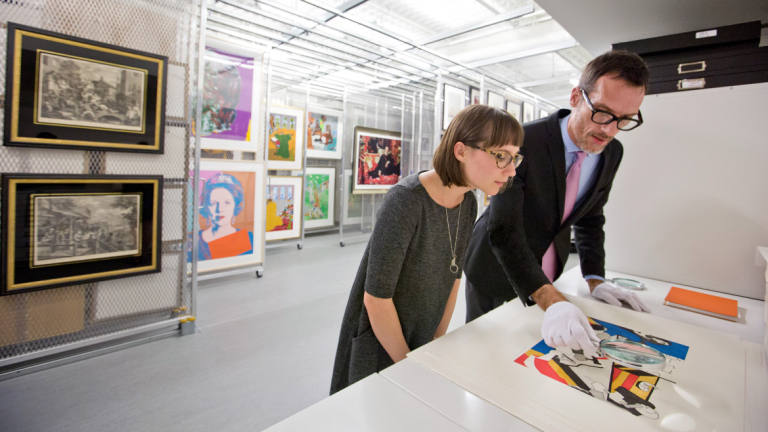 SCAD Museum curator and art history student examining artwork