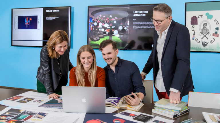 Branded entertainment students collaborating at table with computer