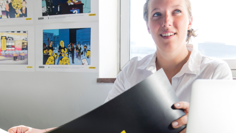 Branded entertainment student reviewing design concepts Branded entertainment student working at desk with design concepts