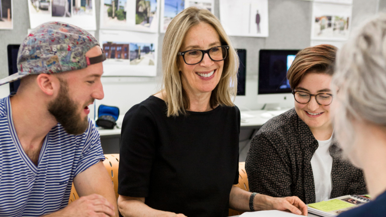 Graphic design students collaborate with a professor in the classroom