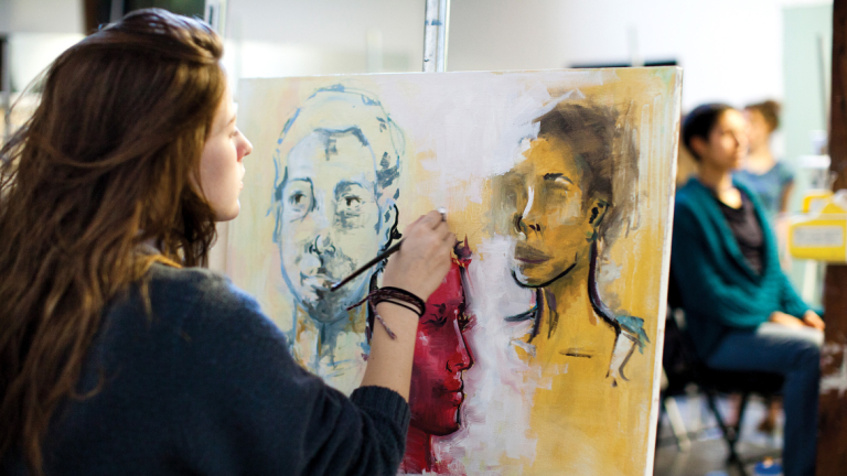 Painting student creating portrait Painting student painting portrait of live model