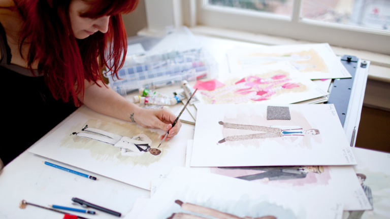 Production design student illustrating costume designs Production design student using watercolors to create costume designs