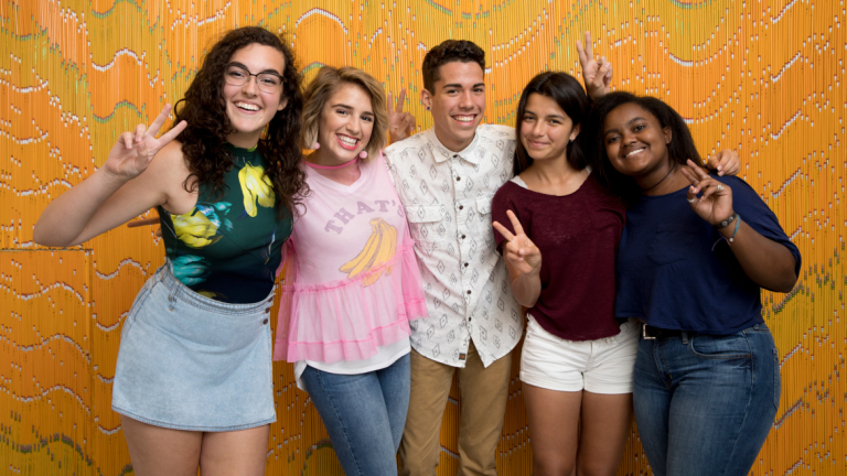 SCAD Savannah Rising Star students pose in front of orange background