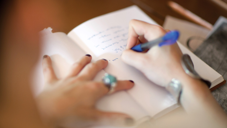 Creative writing student putting pen to paper