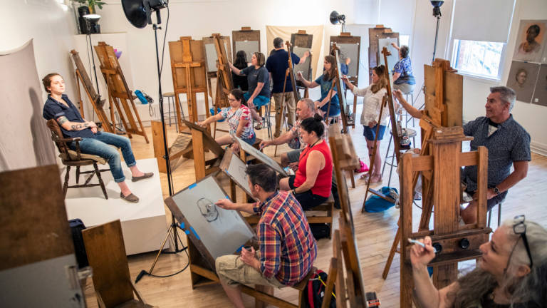 A room full of students and easels drawing a living model.