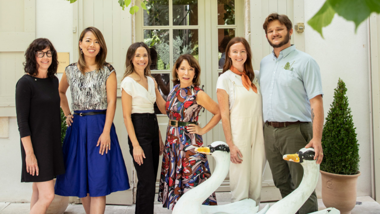 Six individuals posing behind two swam sculptures