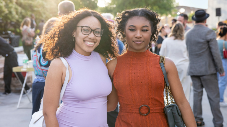 Two smiling female African-American alumni posing for a photo at an alumni event.