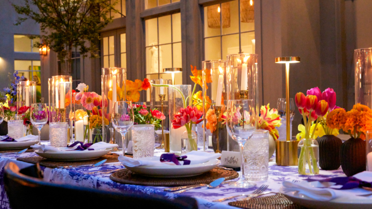 Beautifully decorated outdoor banquet table with vibrant colored floral displays.